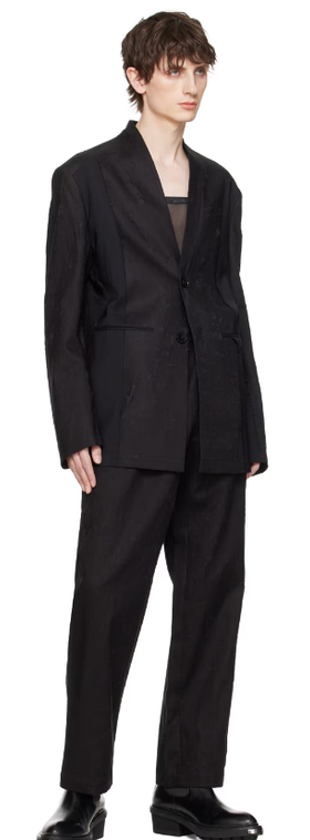 A man wearing a Feng Chen Wang black distressed blazer