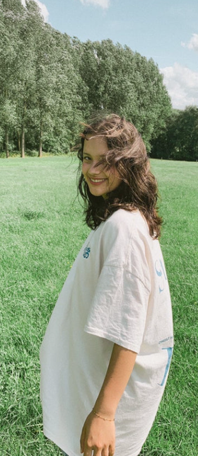 A woman wearing a Jesus Studio white t-shirt with blue screen print on back