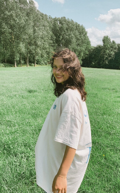 A woman wearing a Jesus Studio white t-shirt with blue screen print on back
