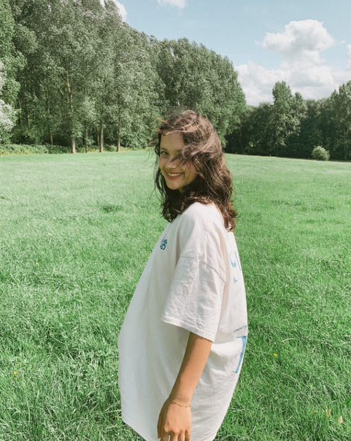 A woman wearing a Jesus Studio white t-shirt with blue screen print on back