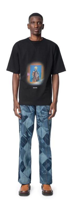 A man wearing a Ahluwalia Studio behind the womxn graphic black t-shirt