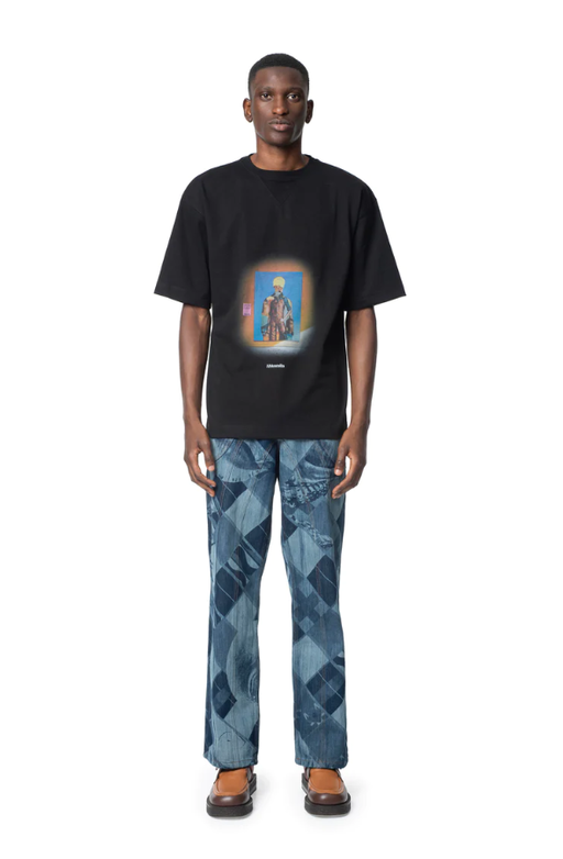 A man wearing a Ahluwalia Studio behind the womxn graphic black t-shirt