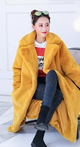 A woman wearing a Spreepicky yellow winter faux fur long fluffy jacket coat