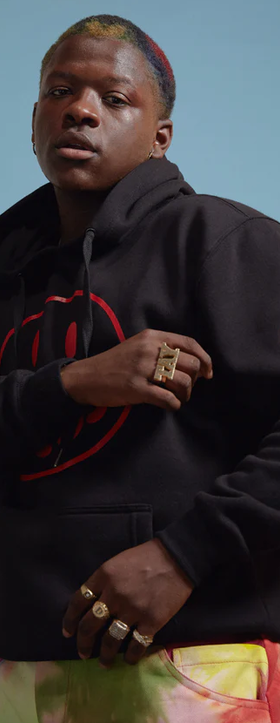 A man wearing a No Sesso acid smiley black hoodie