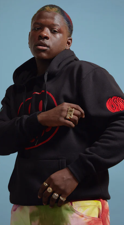 A man wearing a No Sesso acid smiley black hoodie
