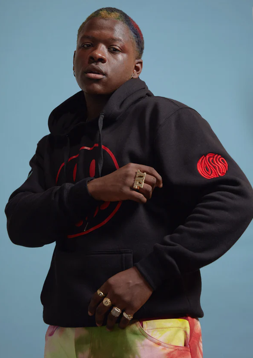 A man wearing a No Sesso acid smiley black hoodie