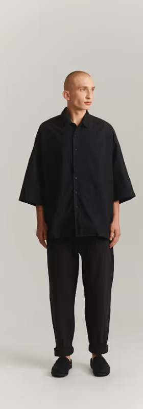 A man wearing a CASEY CASEY black oversize april shirt
