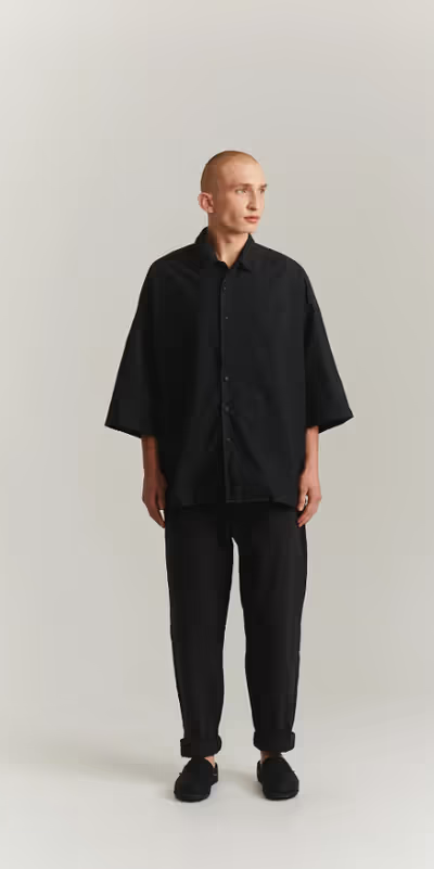 A man wearing a CASEY CASEY black oversize april shirt