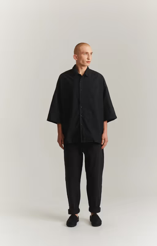 A man wearing a CASEY CASEY black oversize april shirt