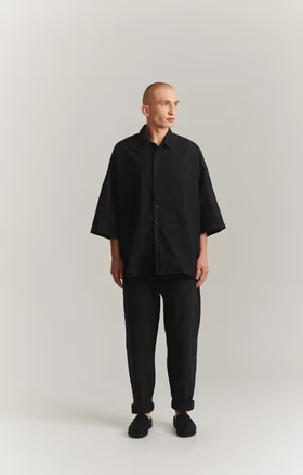 A man wearing a CASEY CASEY black oversize april shirt