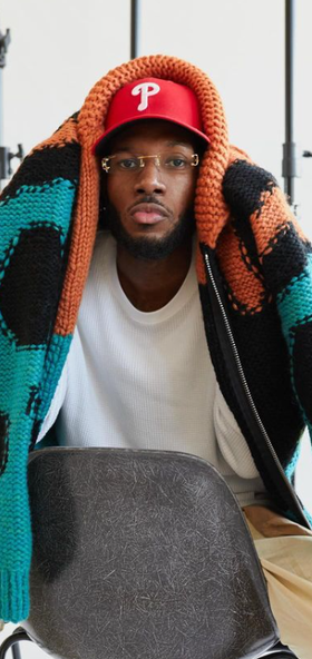 A man wearing a All Caps Studio vermilion / black / turquoise reverse knit virgin wool sweater