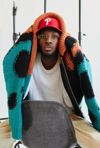 A man wearing a All Caps Studio vermilion / black / turquoise reverse knit virgin wool sweater