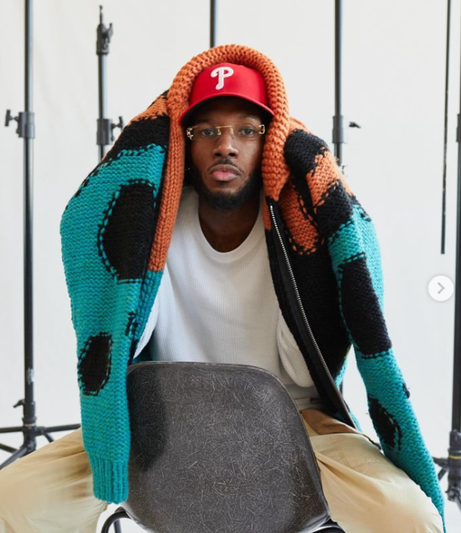 A man wearing a All Caps Studio vermilion / black / turquoise reverse knit virgin wool sweater