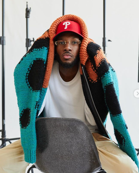 A man wearing a All Caps Studio vermilion / black / turquoise reverse knit virgin wool sweater