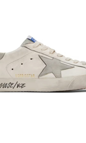 A close up of a pair of a Golden Goose star shoe in white with cursive writing on it