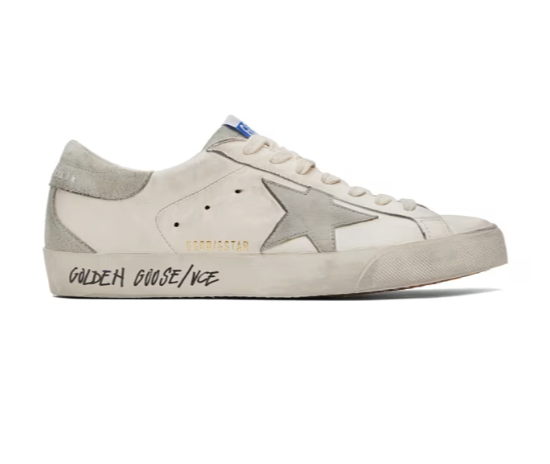 A close up of a pair of a Golden Goose star shoe in white with cursive writing on it