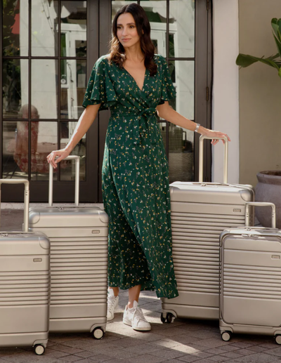 A woman with multiple Arlo Skye suitcases in beige