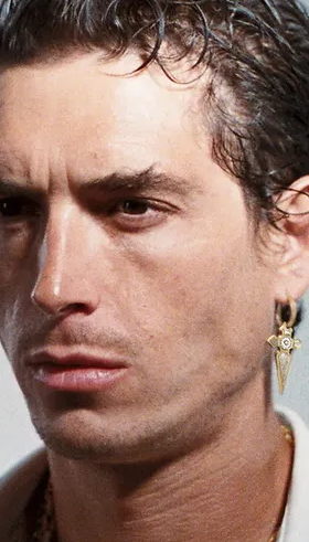 A man wearing a In Gold We Trust Paris earring " cross pendant " - gld