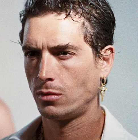 A man wearing a In Gold We Trust Paris earring " cross pendant " - gld