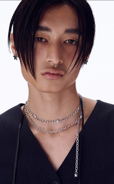 A man wearing a Numbering logo engraved star earrings