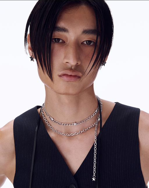 A man wearing a Numbering logo engraved star earrings