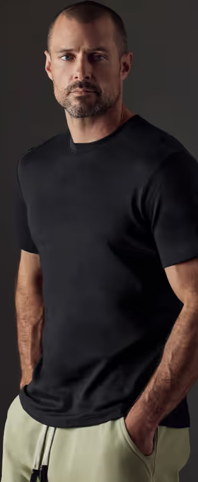 A man wearing a Aether Apparel black emery pima crew tee