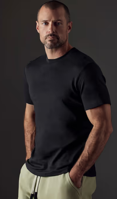 A man wearing a Aether Apparel black emery pima crew tee
