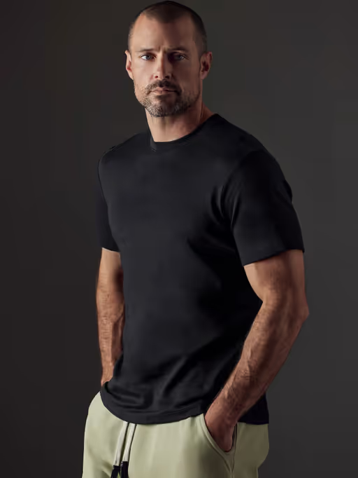 A man wearing a Aether Apparel black emery pima crew tee