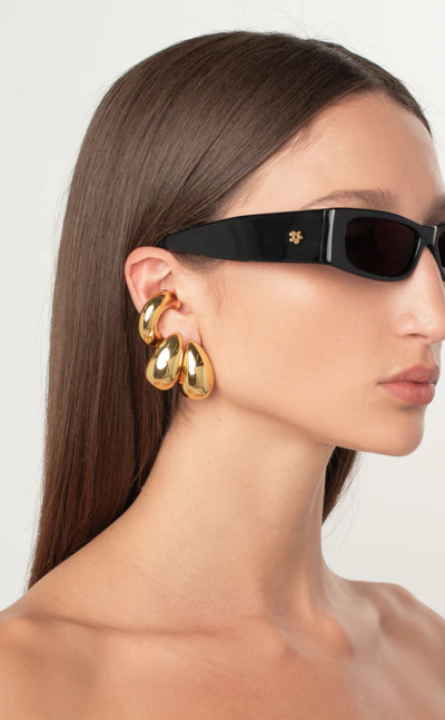 A woman wearing a ÉLIOU varsity ear cuff