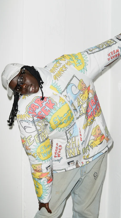 A man wearing a Shark Week NZ white printed puffy jacket