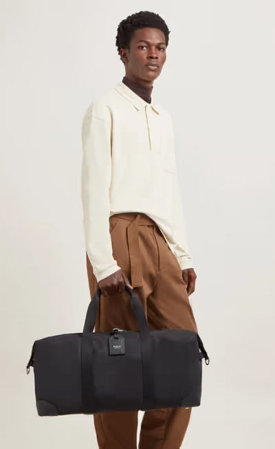 A man carrying Mulberry black heritage medium clipper - nylon bag
