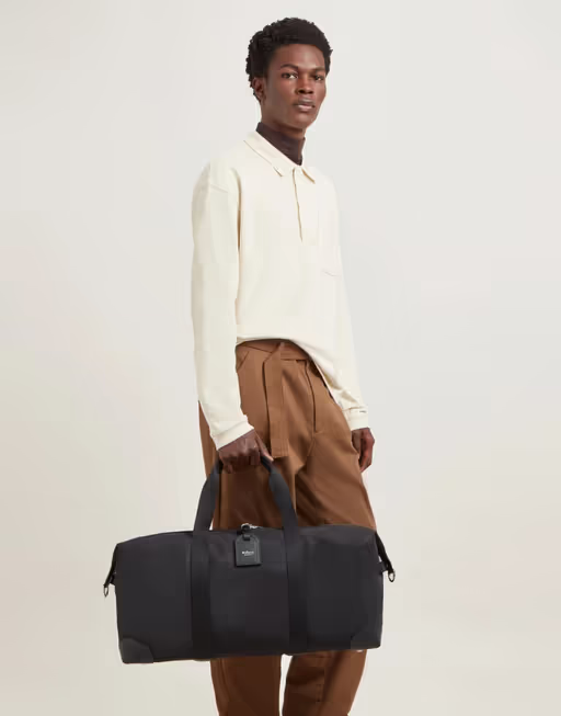 A man carrying Mulberry black heritage medium clipper - nylon bag