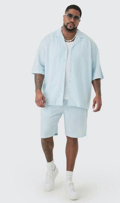 A man wearing a Boohoo Plus oversized light blue button up with matching shorts