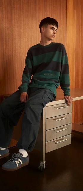 A man wearing Karhu uni striped sweatshirt