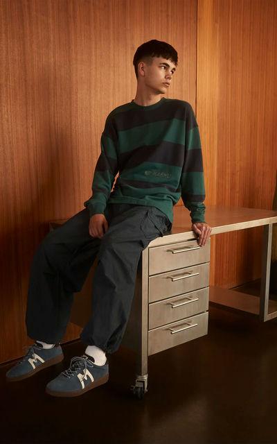 A man wearing Karhu uni striped sweatshirt