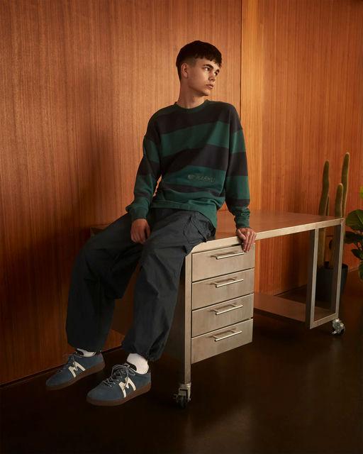 A man wearing Karhu uni striped sweatshirt