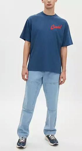 A man wearing Coach dark denim boardwalk specials t shirt in organic cotton
