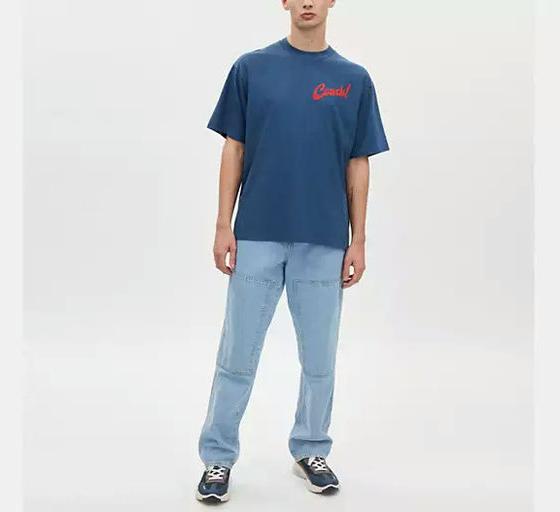 A man wearing Coach dark denim boardwalk specials t shirt in organic cotton