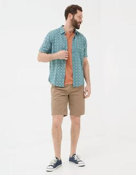 A man wearing Fatface teal green short sleeve snave tile print shirt