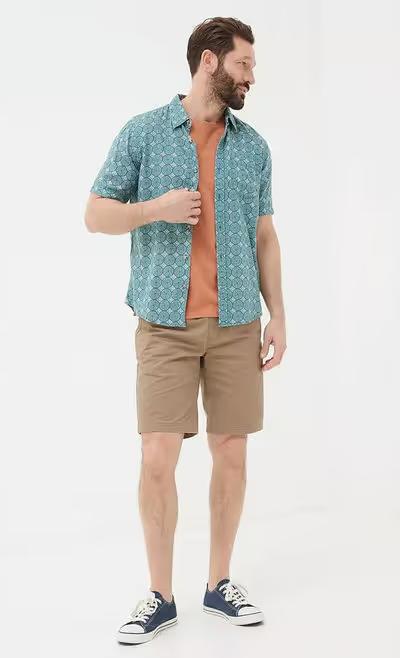 A man wearing Fatface teal green short sleeve snave tile print shirt