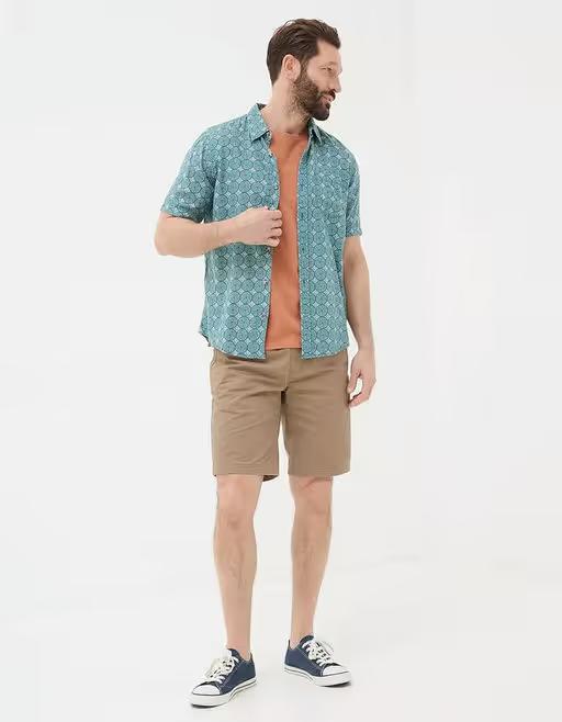 A man wearing Fatface teal green short sleeve snave tile print shirt