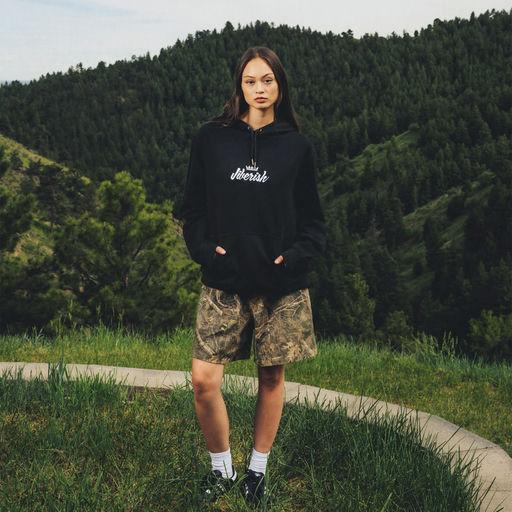 A woman wearing Jiberish Boston Store script french terry hoodie black