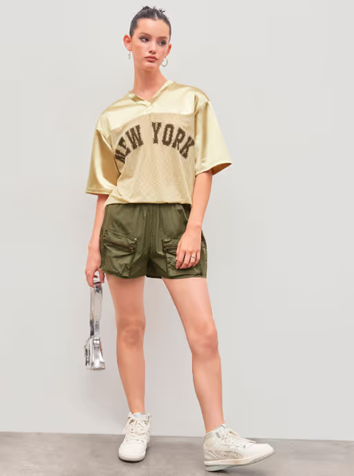 A woman wearing Cider new york satin v-neck oversized short sleeve gold tee