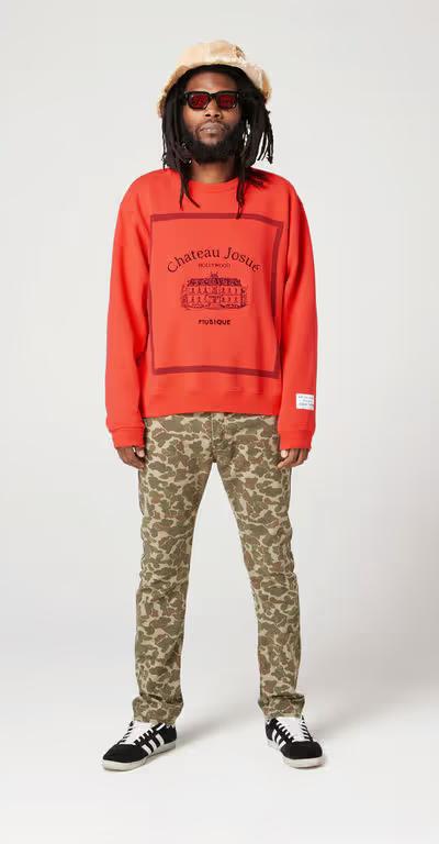 A man wearing Gallery Dept red musique crewneck sweatshirt