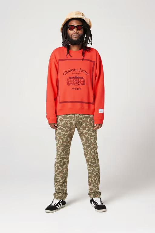 A man wearing Gallery Dept red musique crewneck sweatshirt