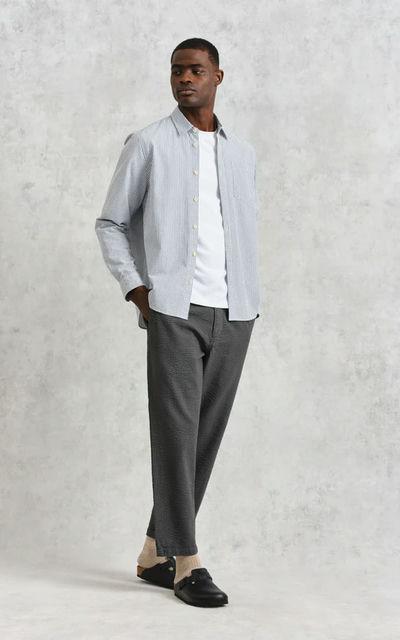 A man wearing Wax shelly shirt navy seersucker stripe