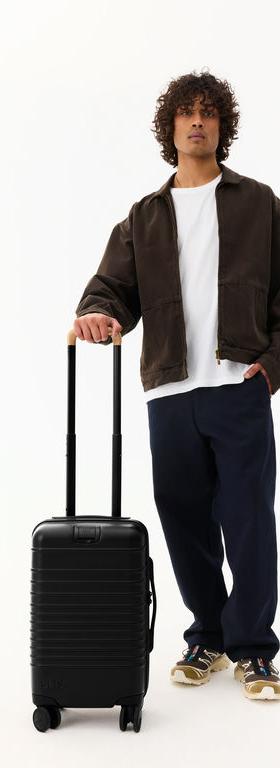A man with BÉIS Travel the small carry-on roller luggage in black