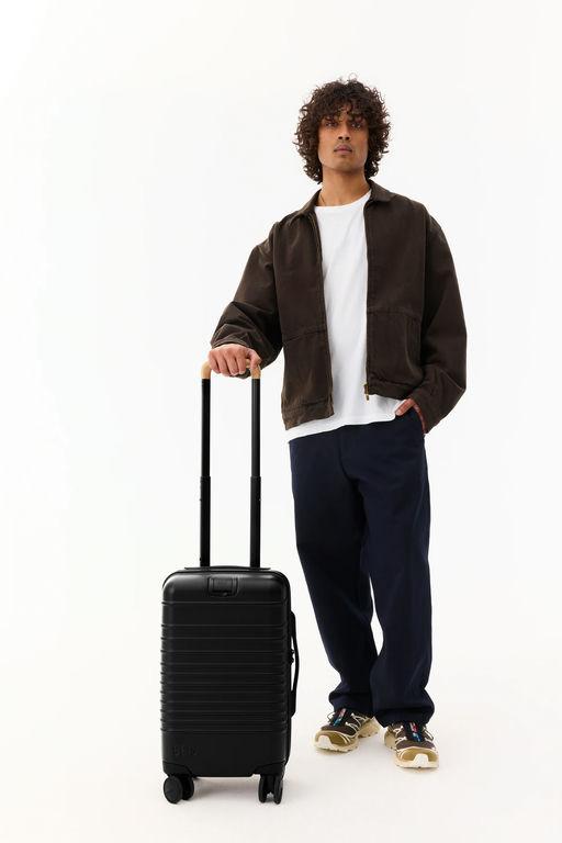 A man with BÉIS Travel the small carry-on roller luggage in black