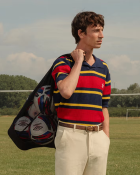 A man wearing a Umbro slacks and striped short-sleeve shirt