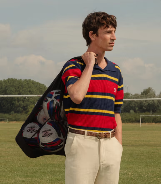 A man wearing a Umbro slacks and striped short-sleeve shirt